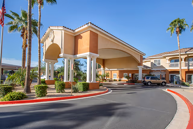 Entrance of Excel Two senior living facility with porte-cochère and palm trees.