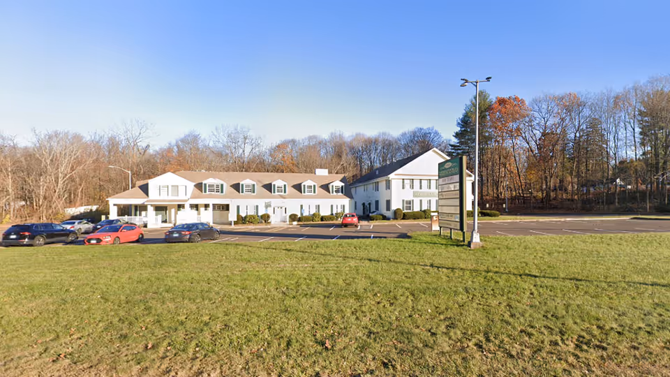 Exterior view of ProNatural Homecare facility with parking lot and trees.