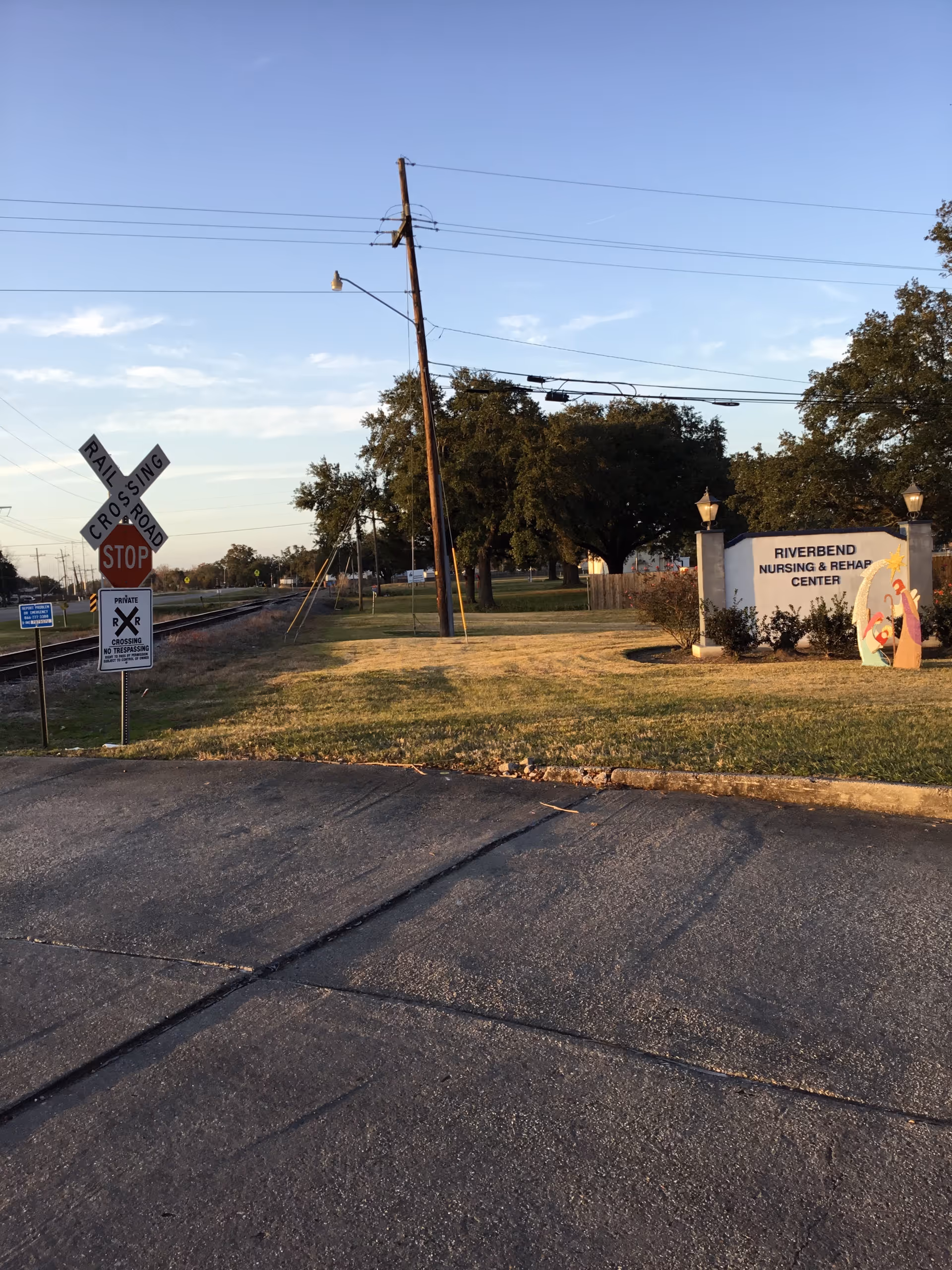 Exterior view of Riverbend Nursing & Rehabilitation Center sign beside road and grassy lawn