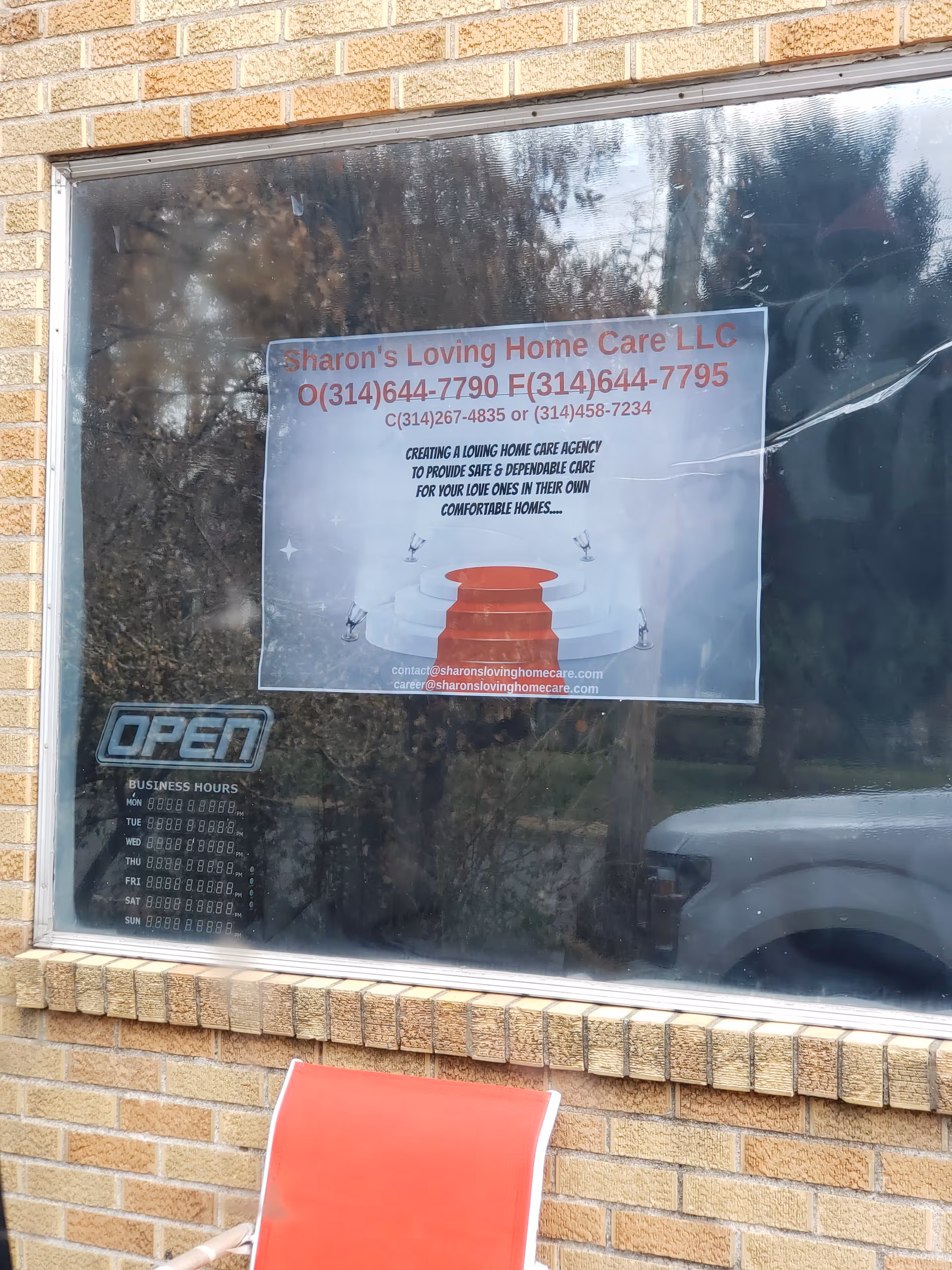 Brick exterior with a window sign advertising Sharon's Loving Home Care LLC and an open sign