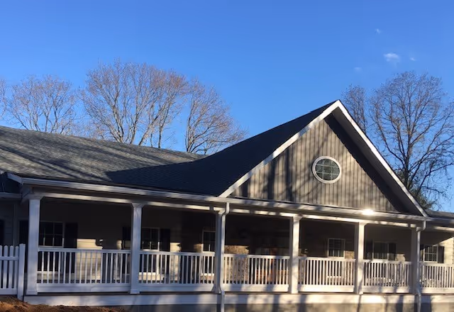 Exterior view of a single-story facility with wraparound porch and gabled roof.