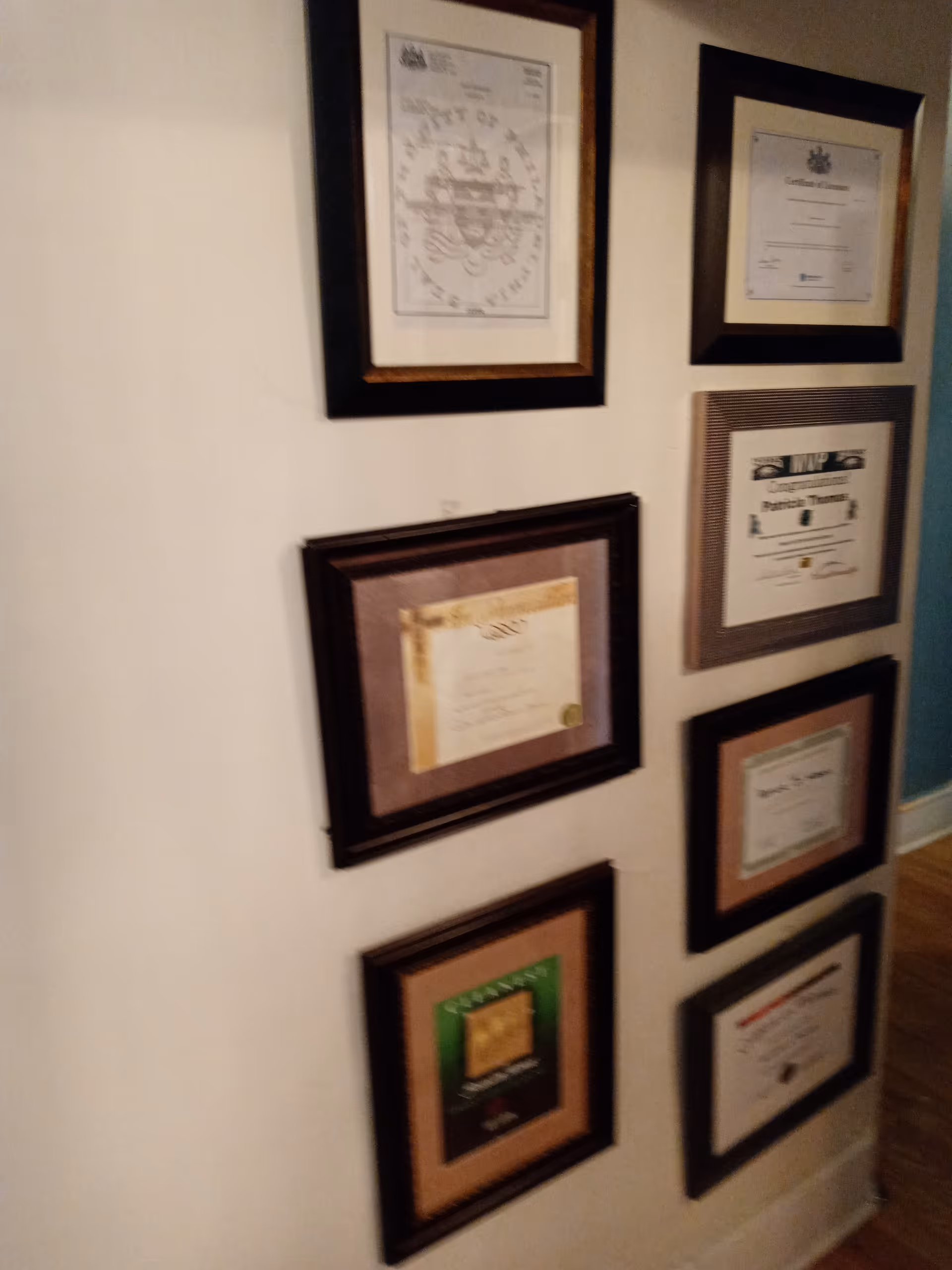 Hallway wall displaying multiple framed certificates and awards.