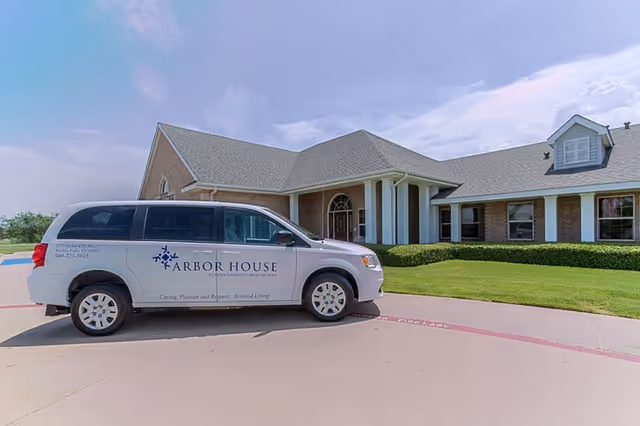 Brick senior living facility with a white Arbor House van parked in front.
