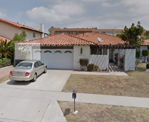 Single-story building with tiled roof, garage, driveway, and a parked car.