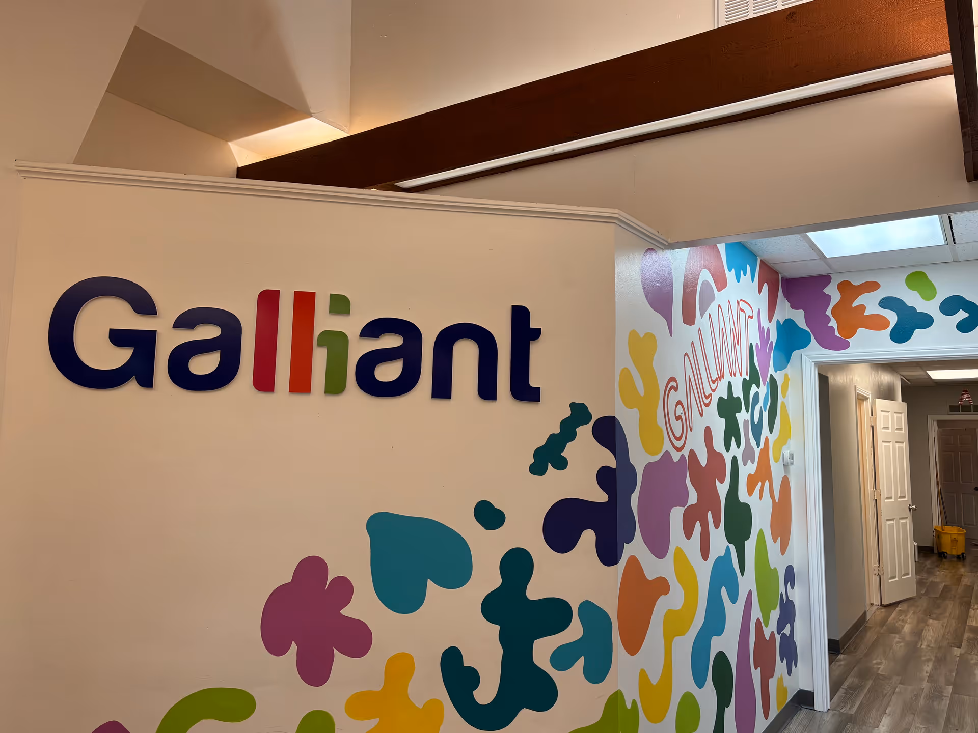 Interior hallway featuring a colorful Galliant Autism Care sign and mural walls.