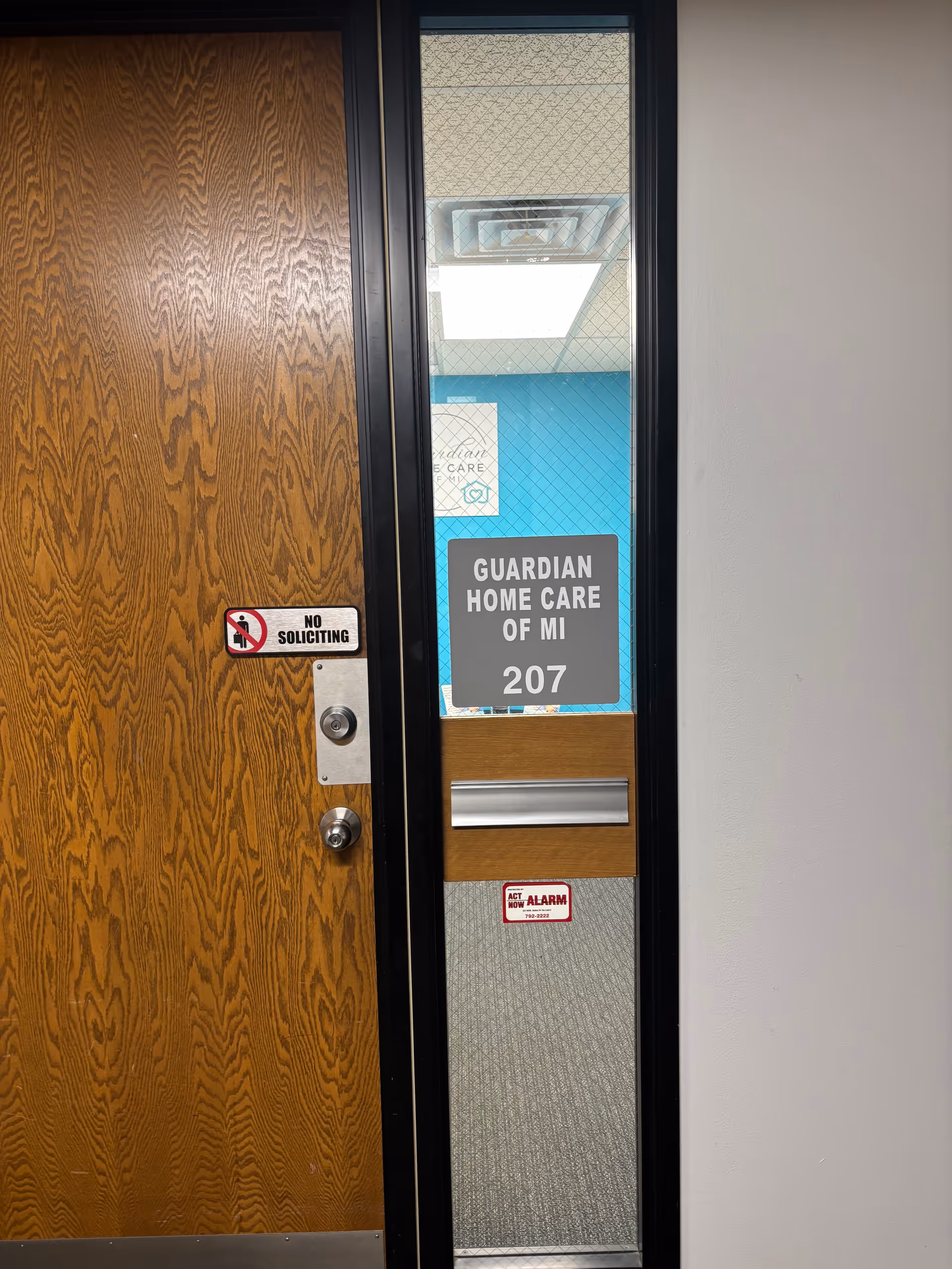 Wooden door with Guardian Home Care of MI 207 sign and no soliciting sticker.