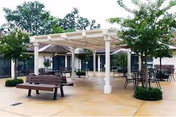 Outdoor patio with a pergola, benches, and tables at Pleasanton Nursing and Rehabilitation Center.