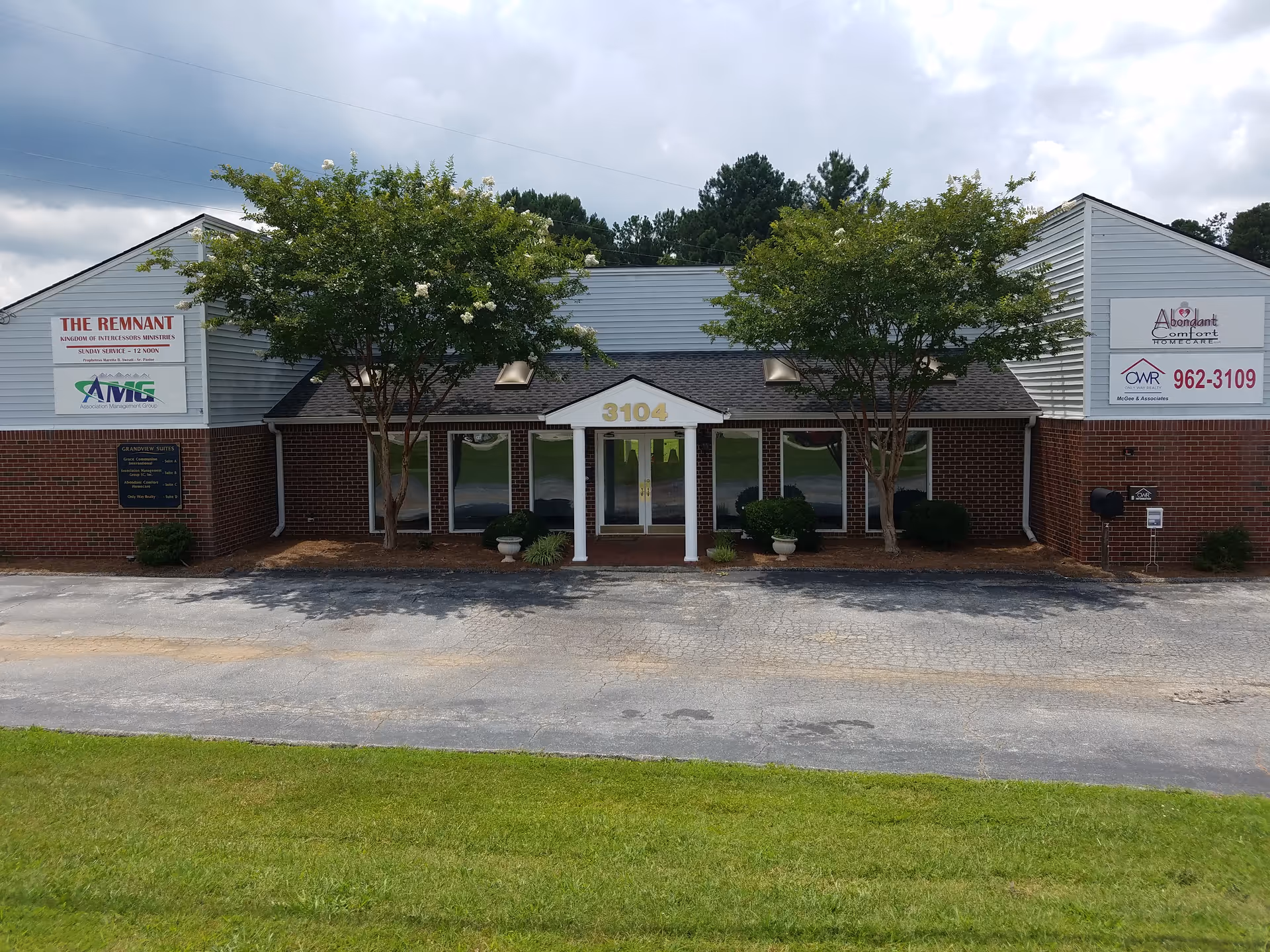 Front view of a single-story brick senior living facility with a central entrance and trees.