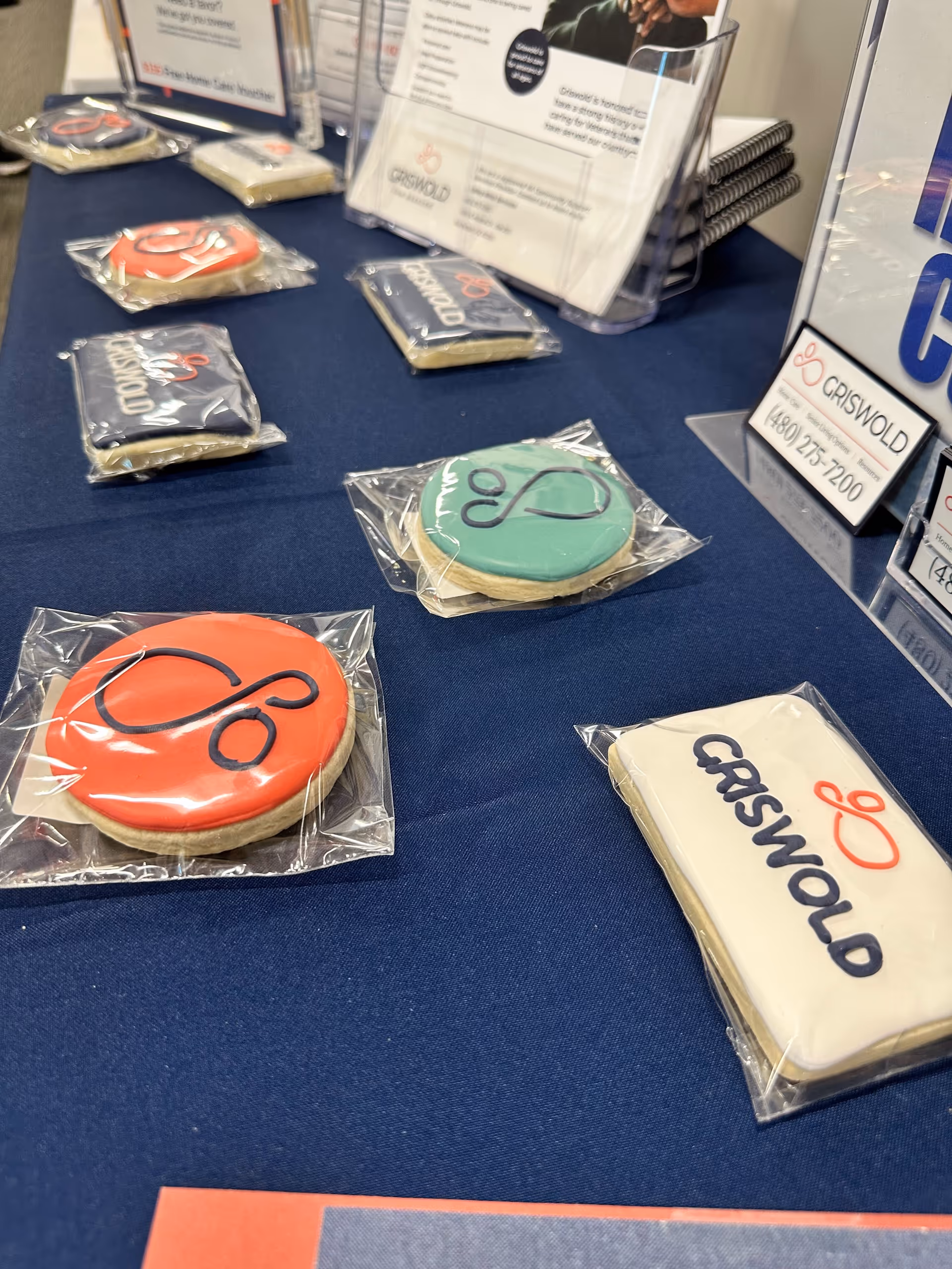 Table covered with branded cookies and brochures at Griswold Home Care Scottsdale booth