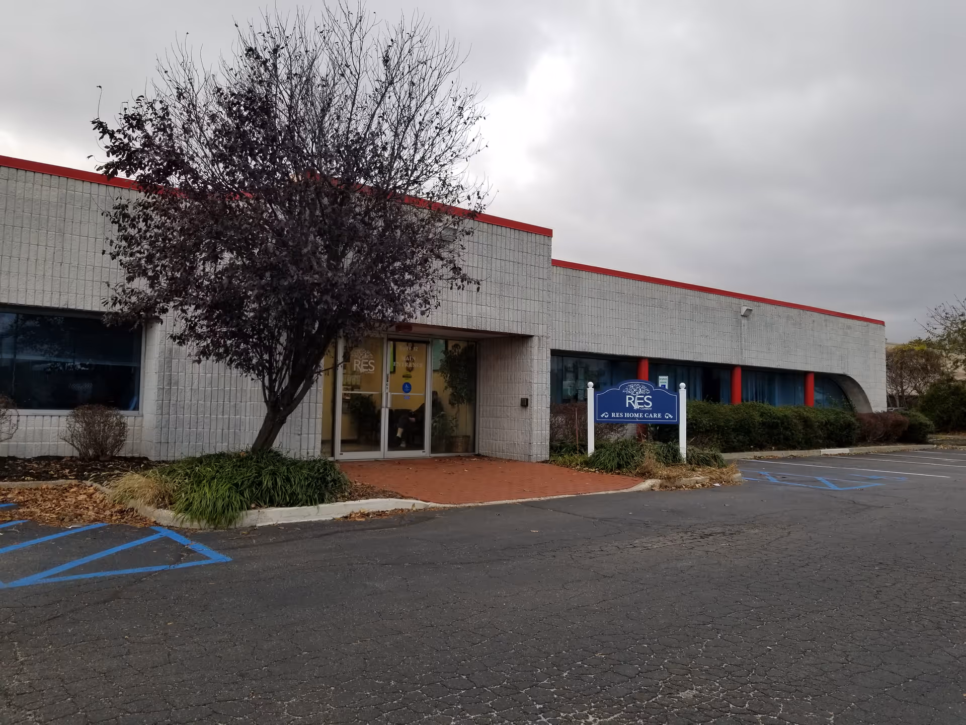 Exterior view of RES Home Care building with a tree, parking lot, and sign.