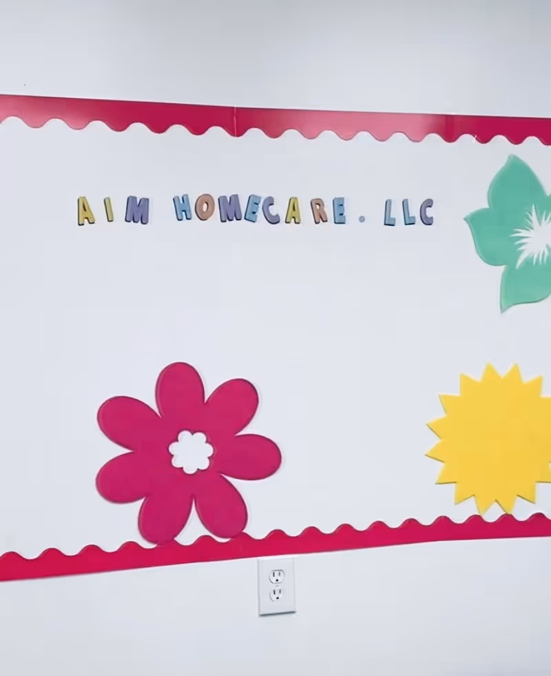 AIM Homecare LLC sign with colorful flower mural on bright wall; outlet visible.
