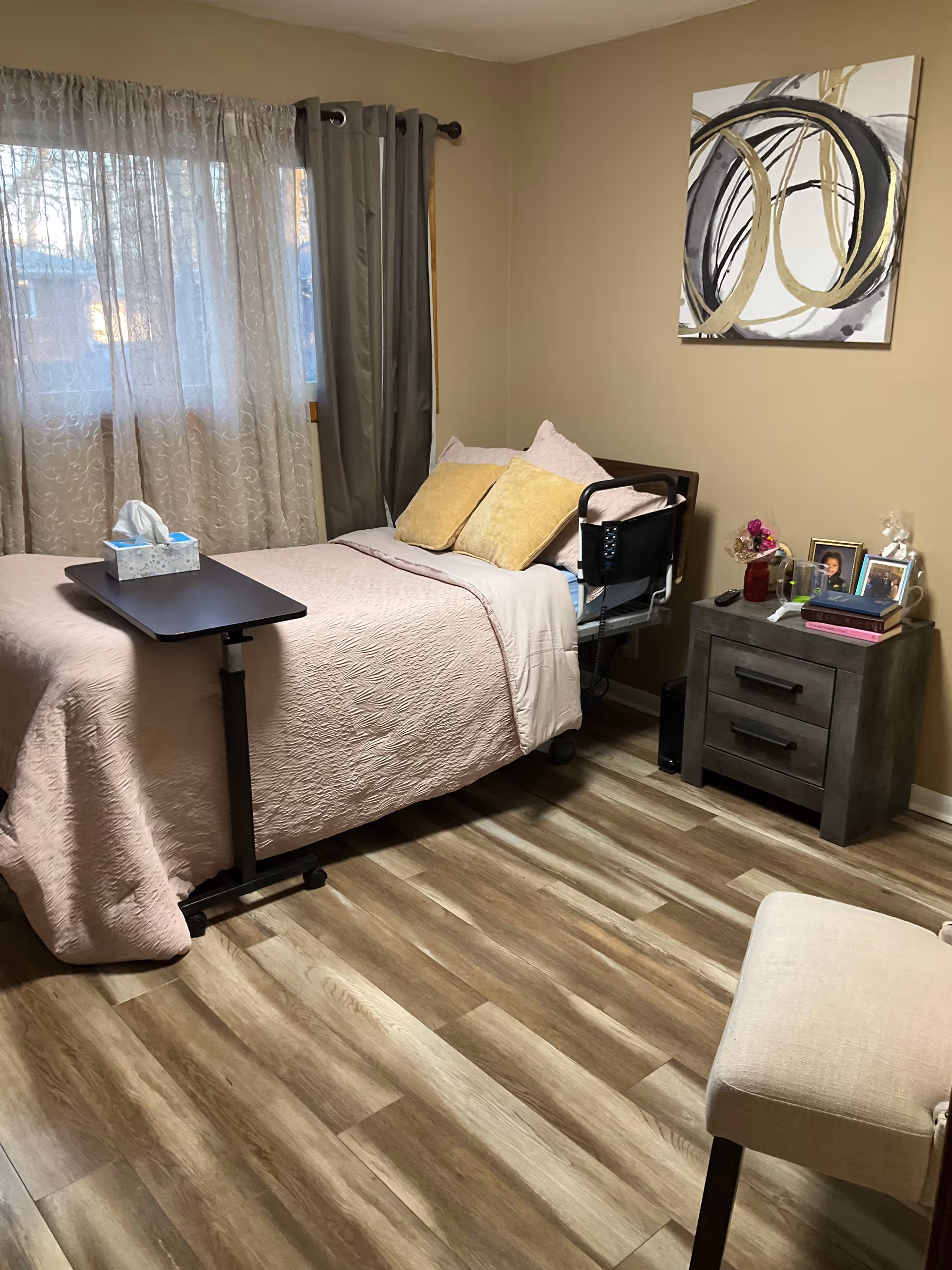 A cozy bedroom with a bed, nightstand, window, and wall art.