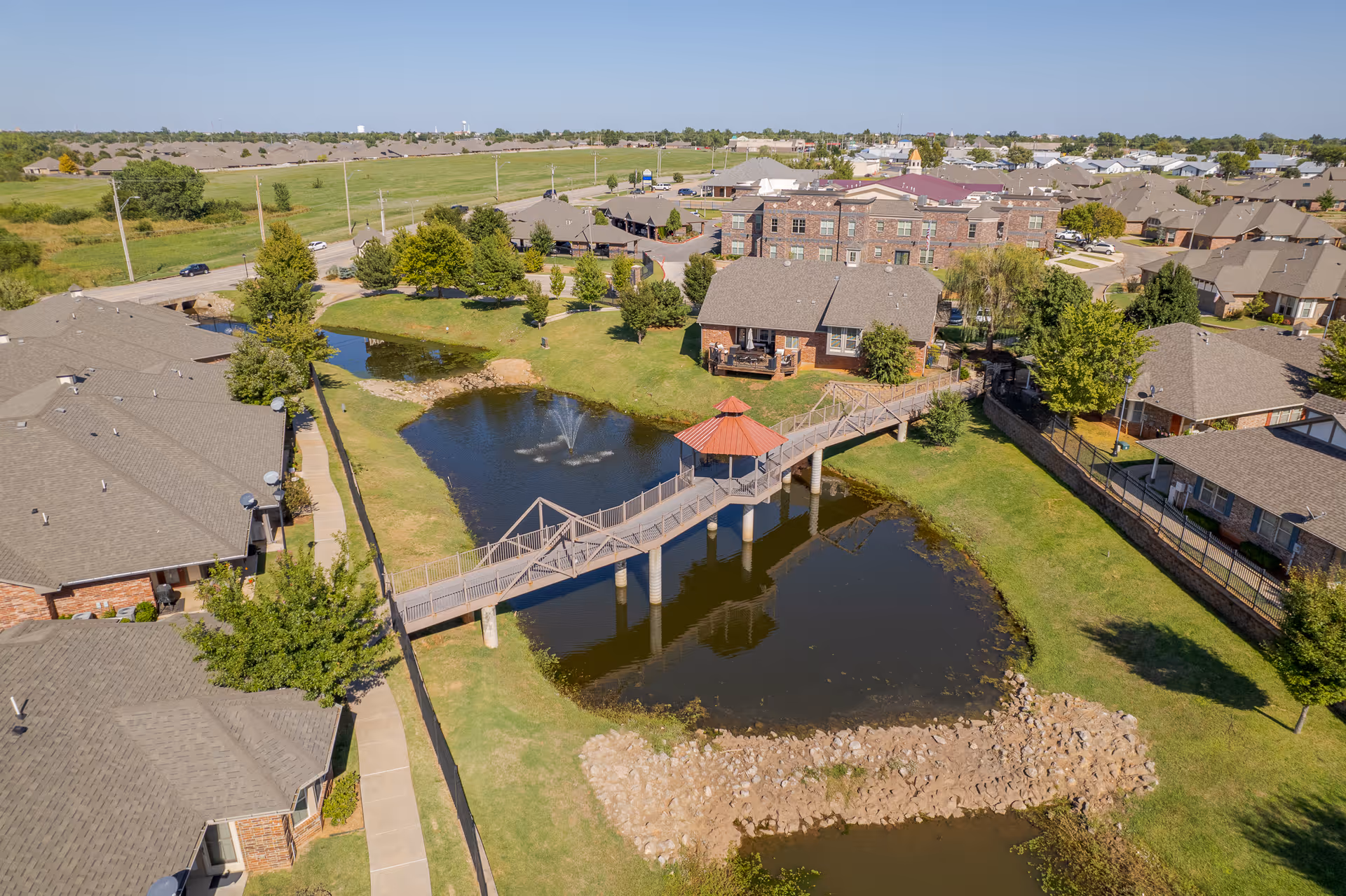 Aerial view of Grace Pointe senior living campus showing pond, bridge, and buildings.