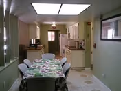 A dining area in a senior living facility with a long table and floral tablecloth.