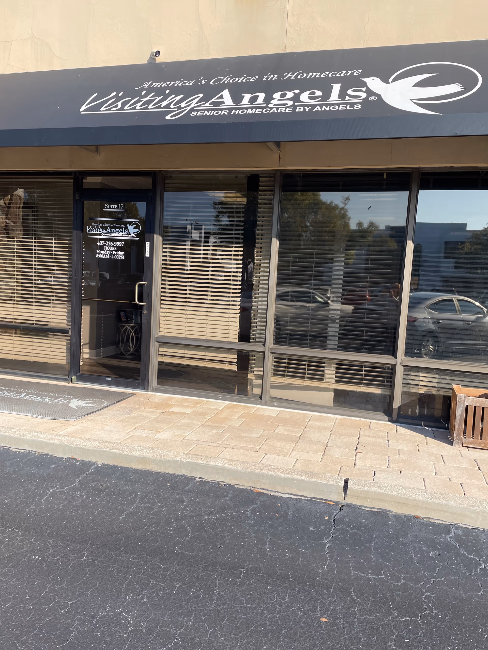 Exterior of Visiting Angels storefront with large sign, glass doors, and parked cars