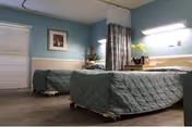 Two twin beds with green quilts in a teal shared bedroom.