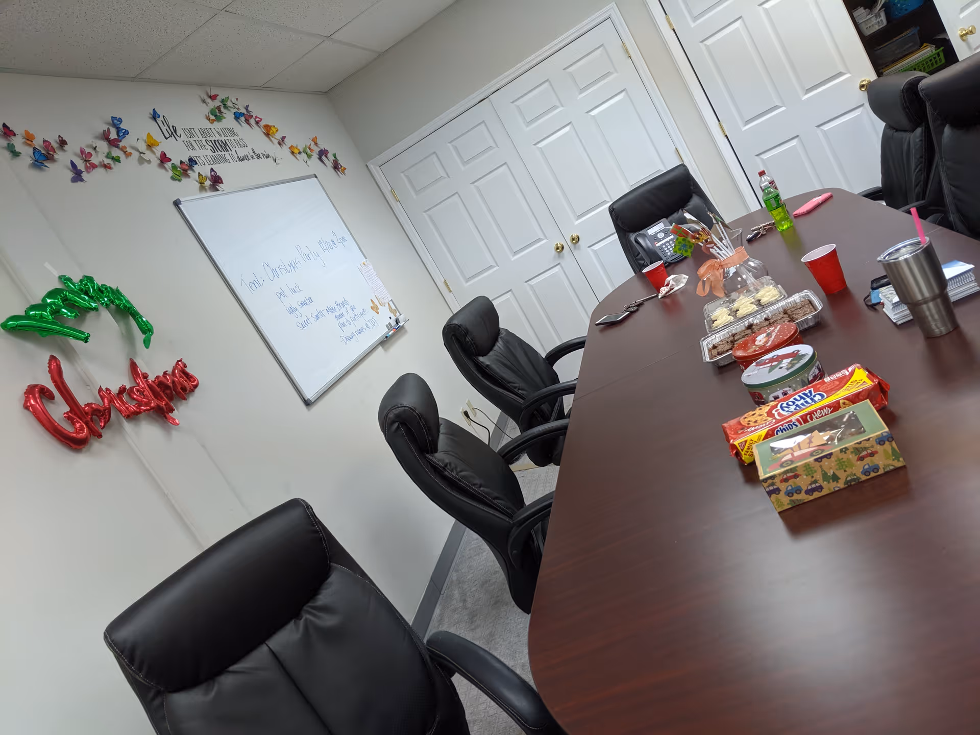 Interior conference room with a long table, black chairs, whiteboard, and snacks.