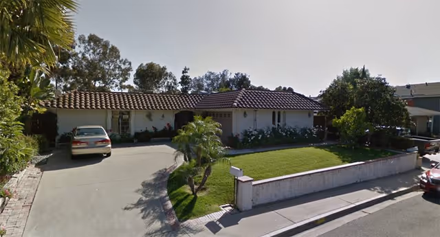 Single-story facility front view with driveway, lawn, and parked cars