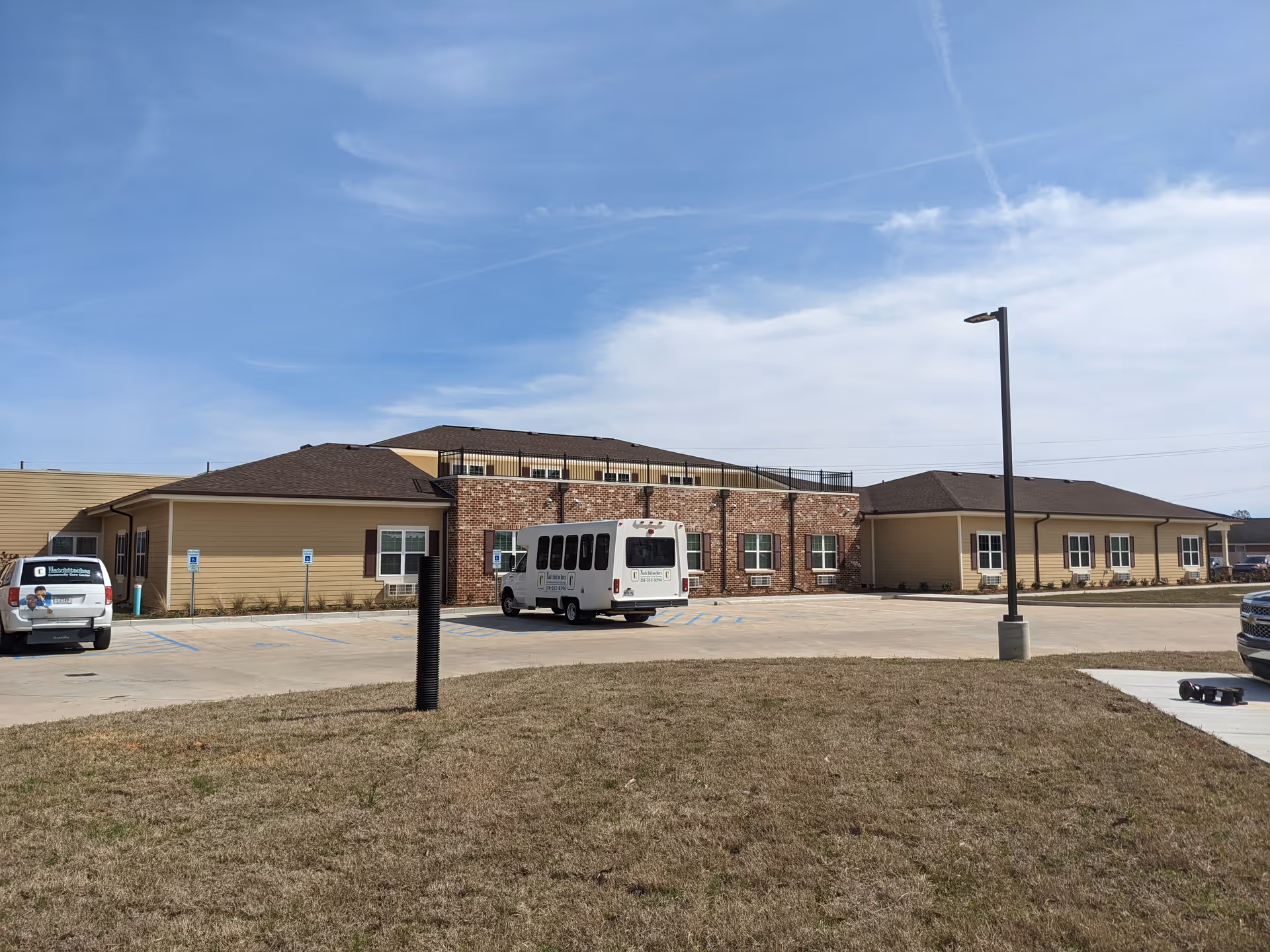 Exterior view of Natchitoches Community Care Center with a white bus in the parking lot.