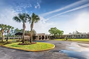 Exterior view of a single-story facility with a circular driveway and palm trees.