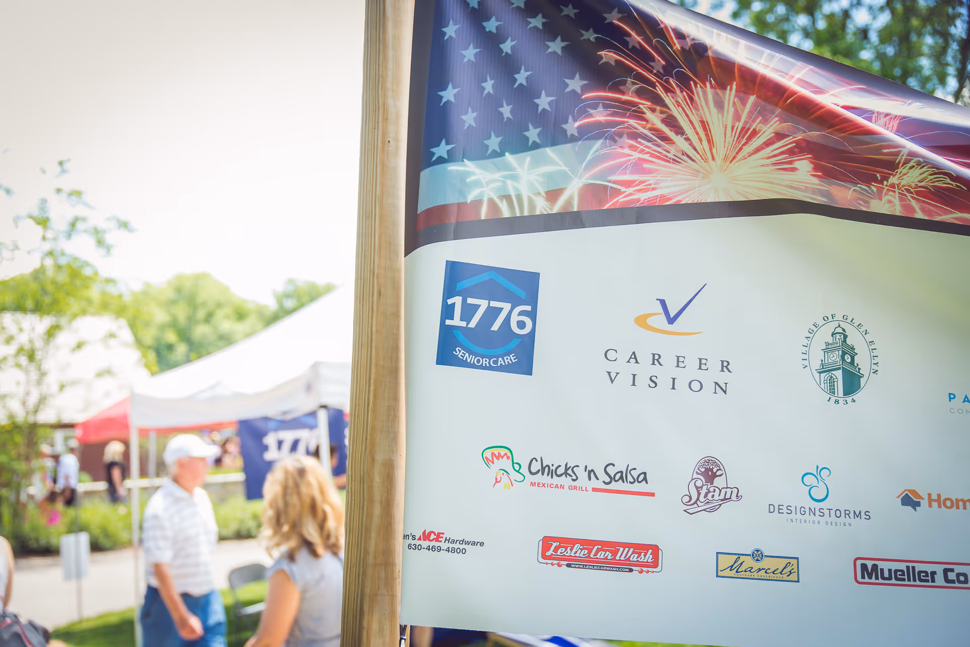 Outdoor event banner displays 1776 Senior Care and sponsors beside tents and attendees
