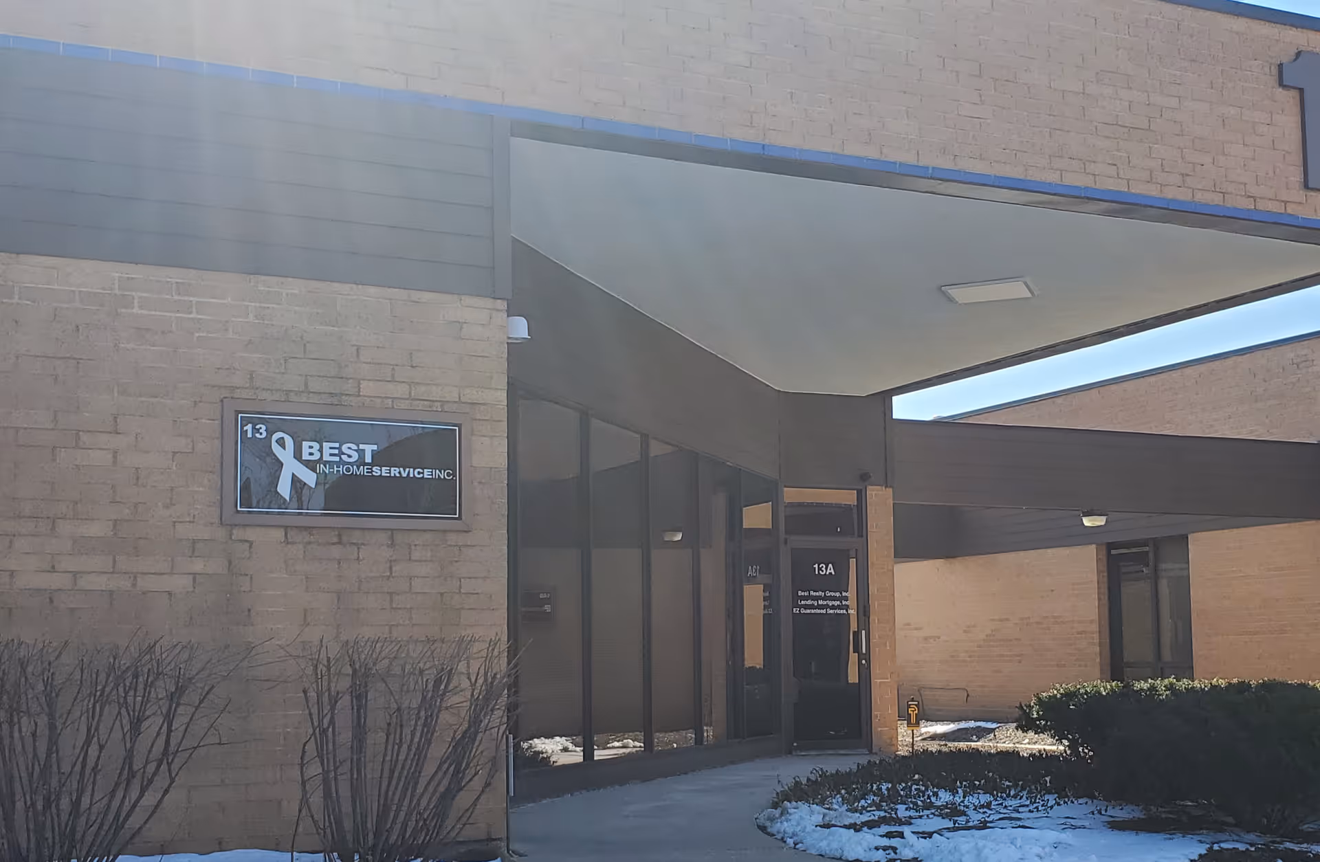 Exterior of Best In-Home Service Inc. building with glass doors and snow.