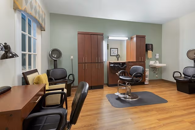 Hair salon area in a senior living facility with styling chairs, mirrors, and stations.