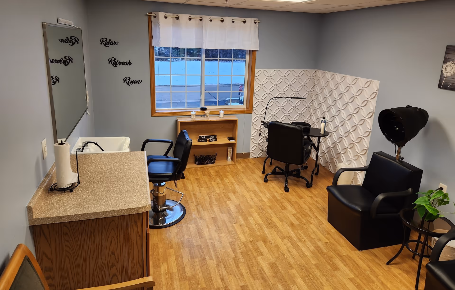 A small senior living facility salon with chairs, a sink, mirror, and styling station.