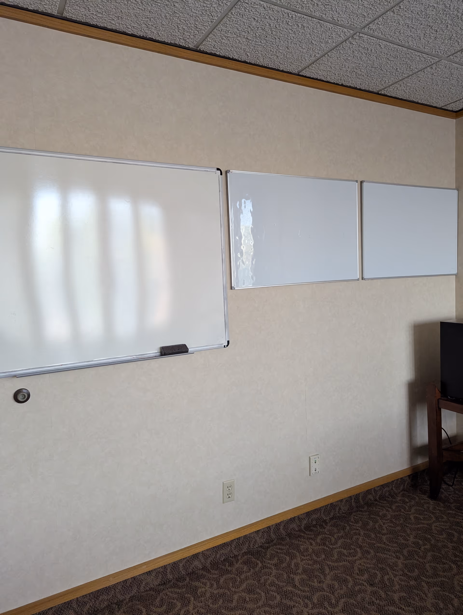 Interior room in a senior living facility with whiteboards on beige walls and carpet.