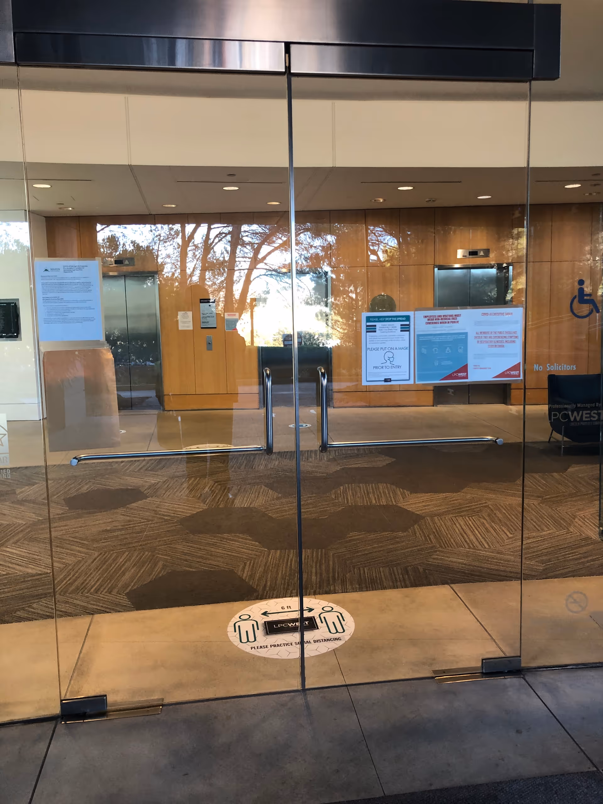 Glass double doors lead into a modern lobby with wood panel walls and posted signs.