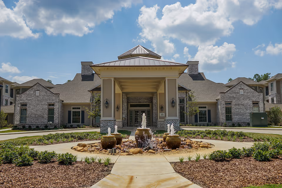 Front view of The Claiborne at Hattiesburg independent living facility with a central entrance and fountain.