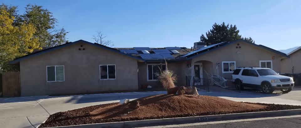 Single-story beige assisted living facility with solar panels and a white SUV in front.