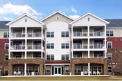 Exterior view of a multi-story senior living building with balconies and brick base.