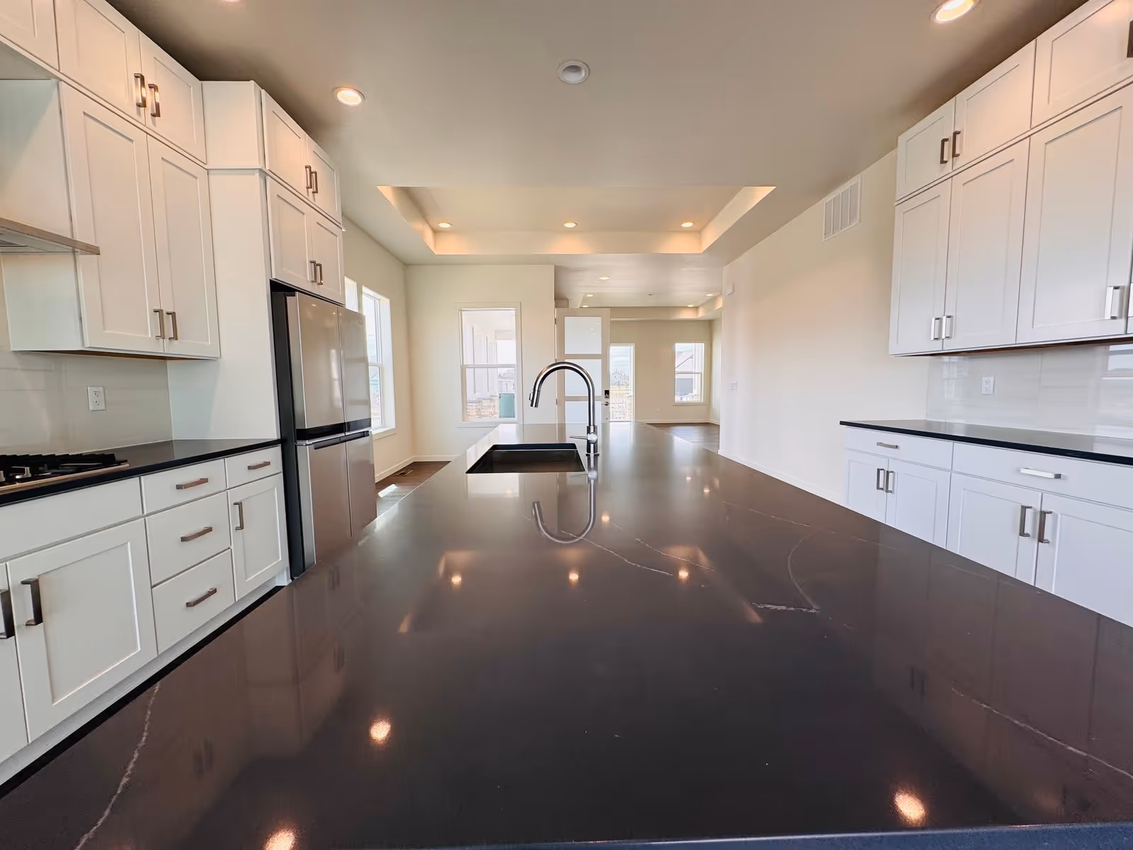 Bright modern kitchen with white cabinets, a large dark countertop island, and stainless appliances.