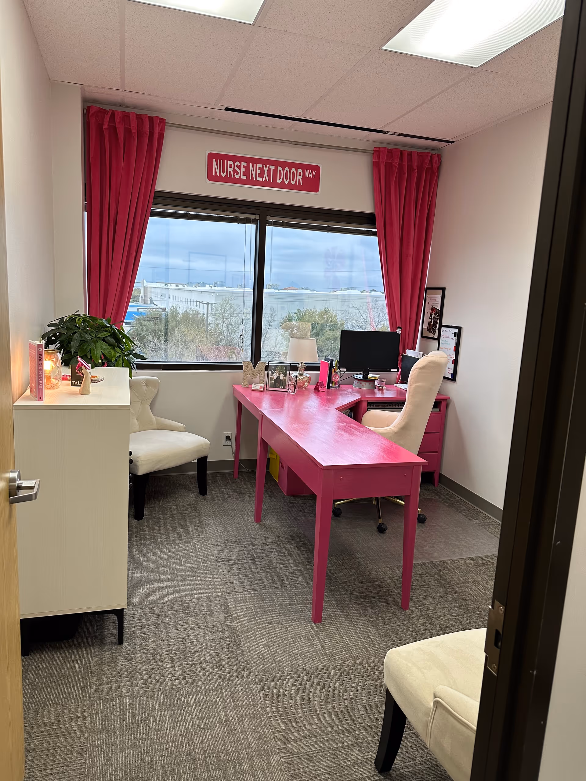 Nurse Next Door office with pink desk, pink curtains, and a large window view.