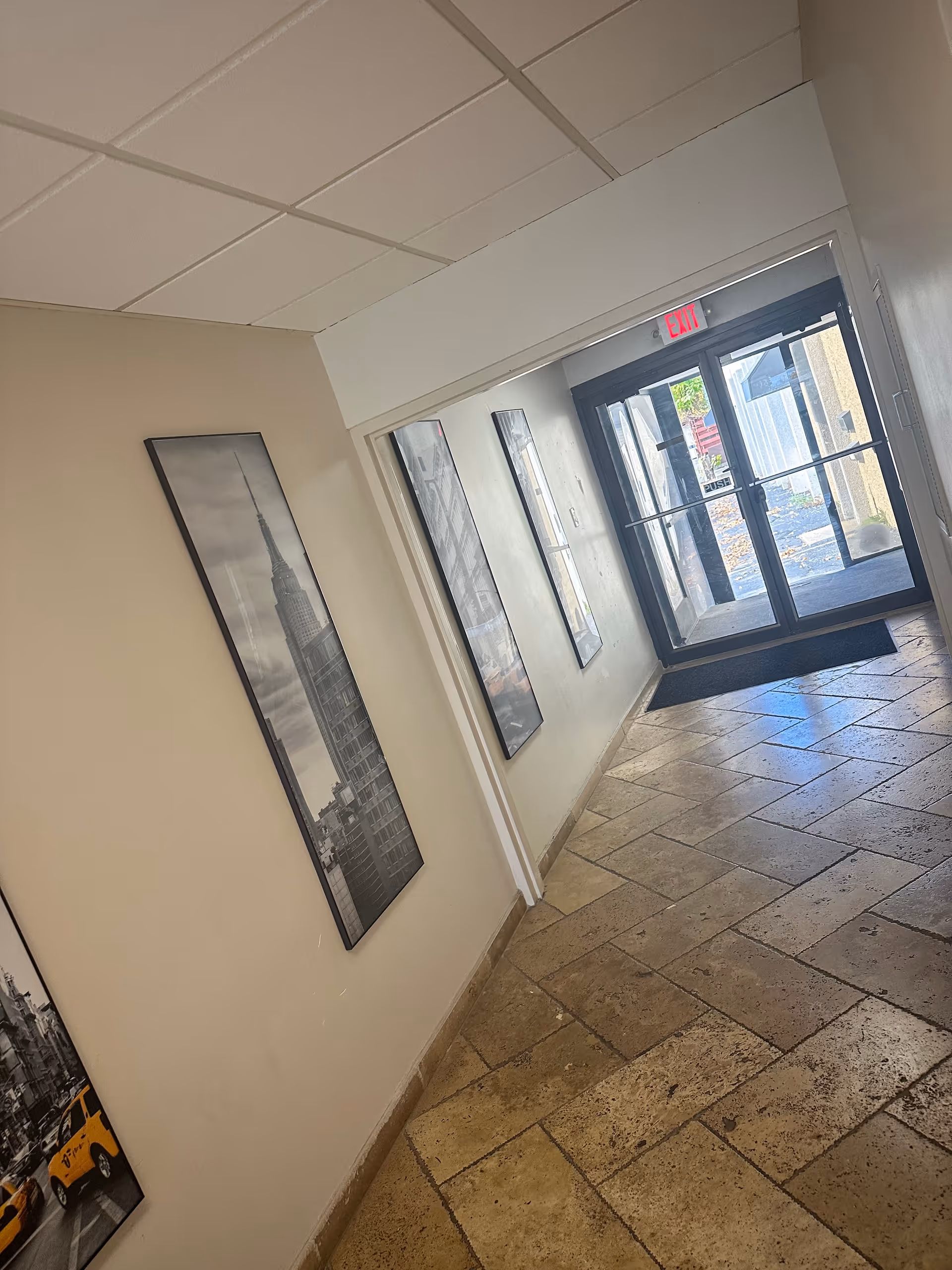 Interior hallway with black and white cityscape art on walls and a glass exit door.