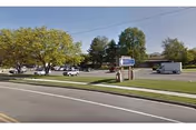 Street view shows a grassy median, trees, and a senior living facility sign in front.