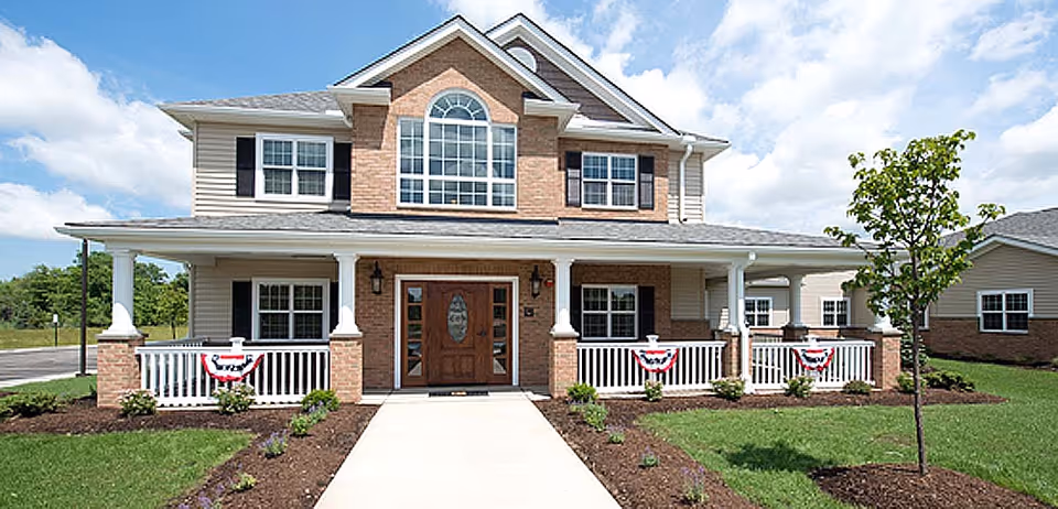 Two-story senior living facility with a covered front porch and bunting.