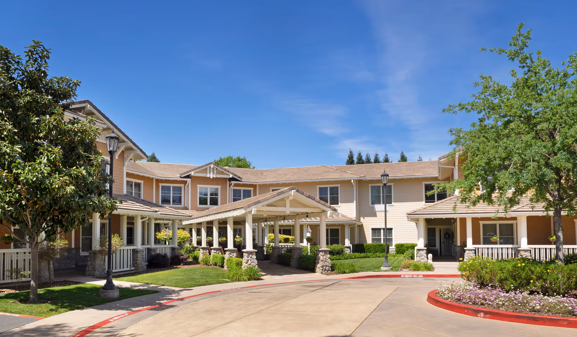 Sunrise of Carmichael exterior facility with covered entrance, manicured landscaping, and blue sky.
