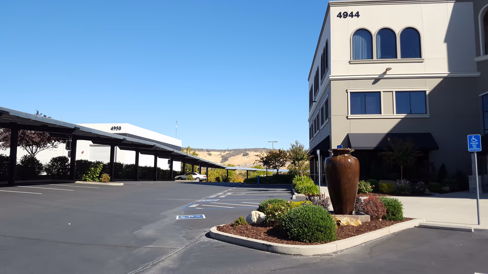 Exterior view of a multi-story facility with a parking lot and landscaped surroundings.