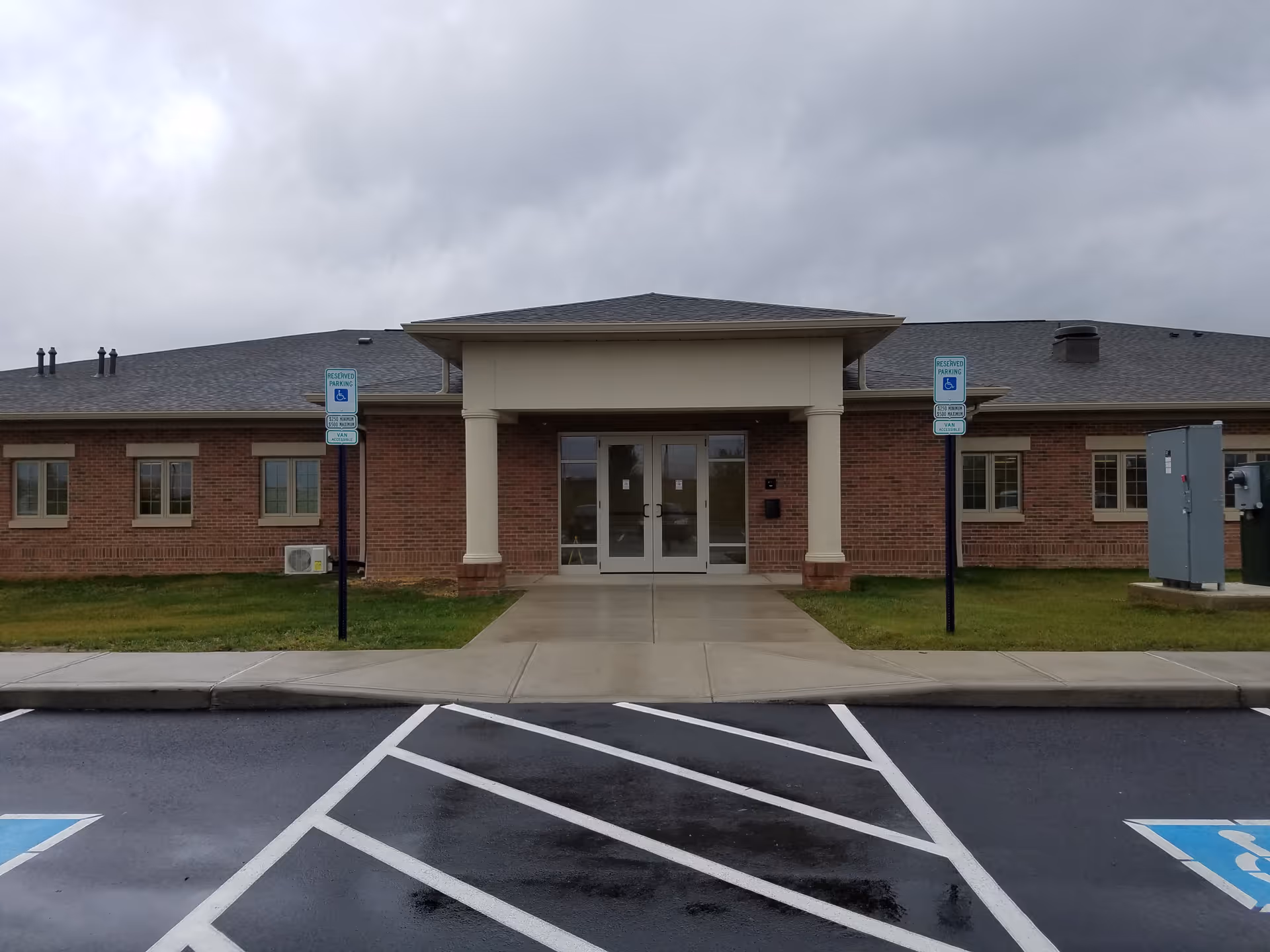 Brick building with a covered front entrance and accessible parking spaces.