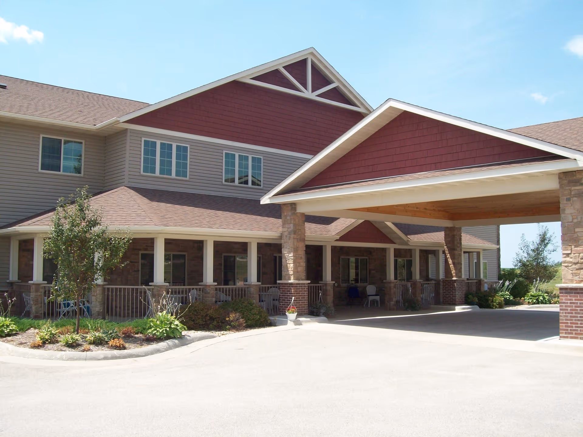 Exterior view of a senior living facility with a covered entrance and landscaping.