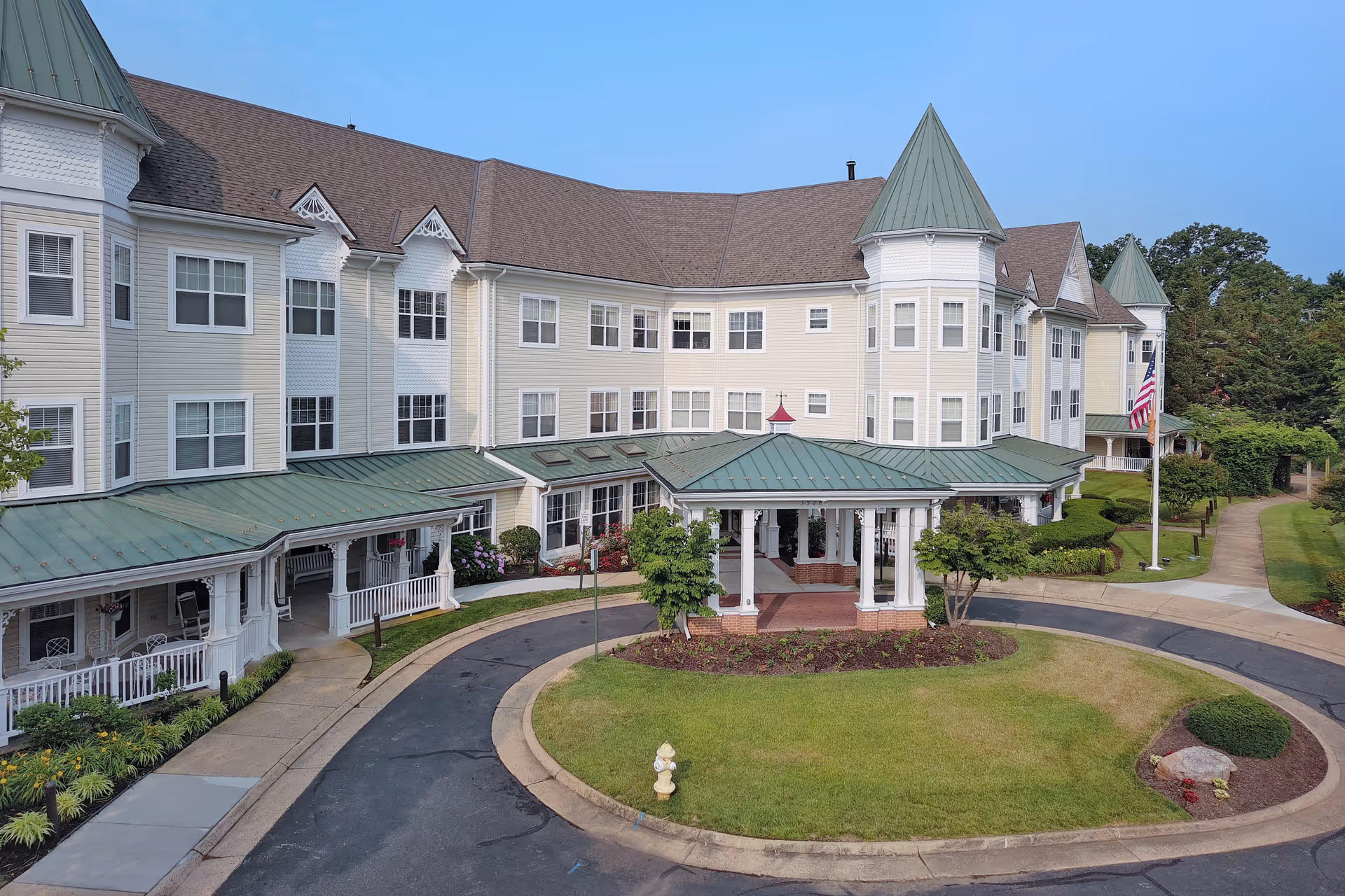 A large, light-colored senior living facility with circular driveway and green-roofed towers.