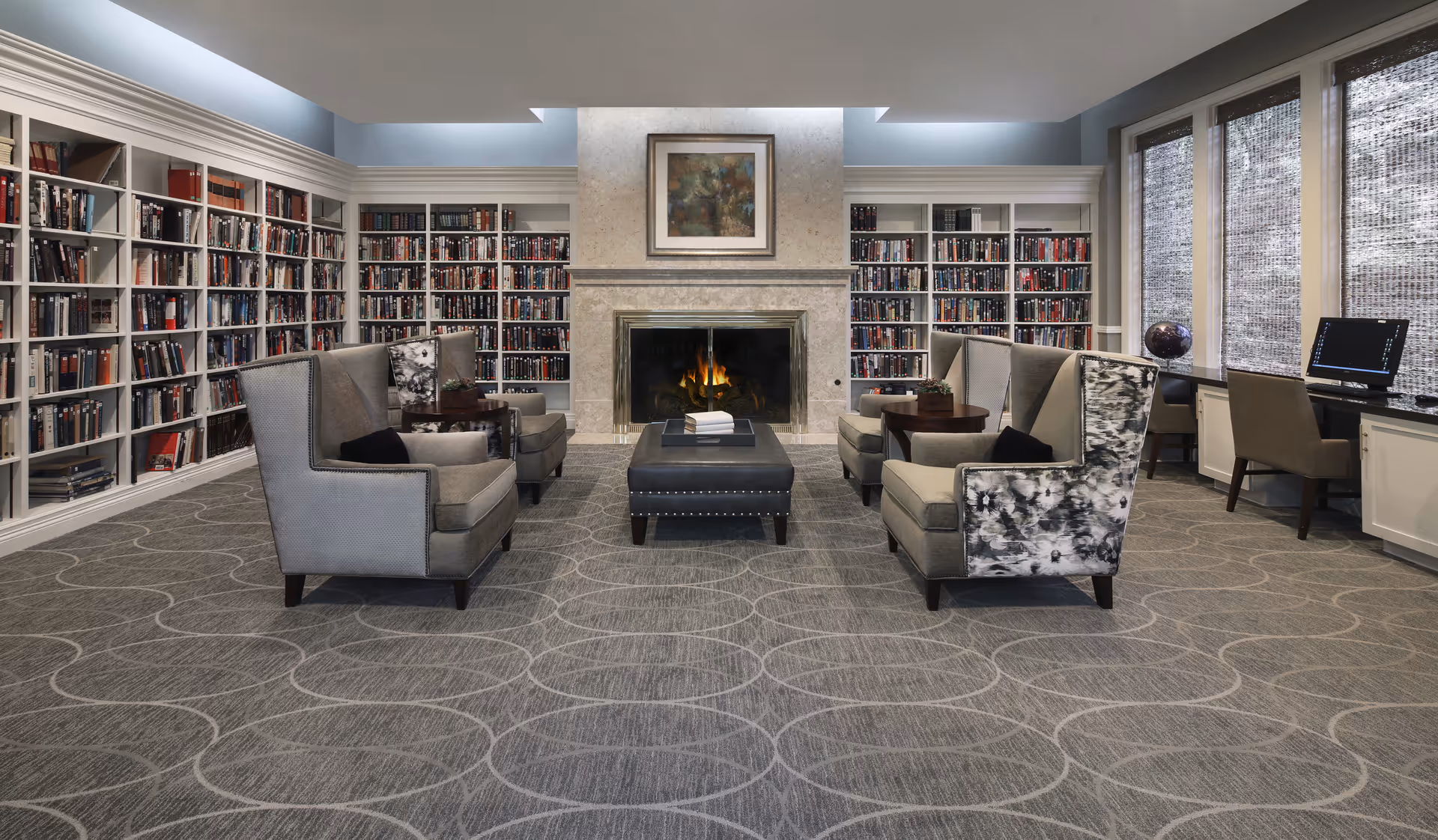 Lounge area with fireplace, large bookshelves, and multiple seating arrangements.