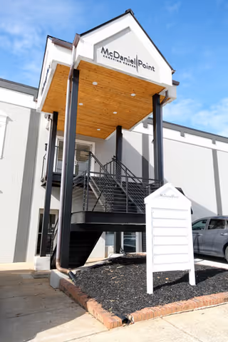Exterior view of a modern senior care facility entrance with stairs and signboard.