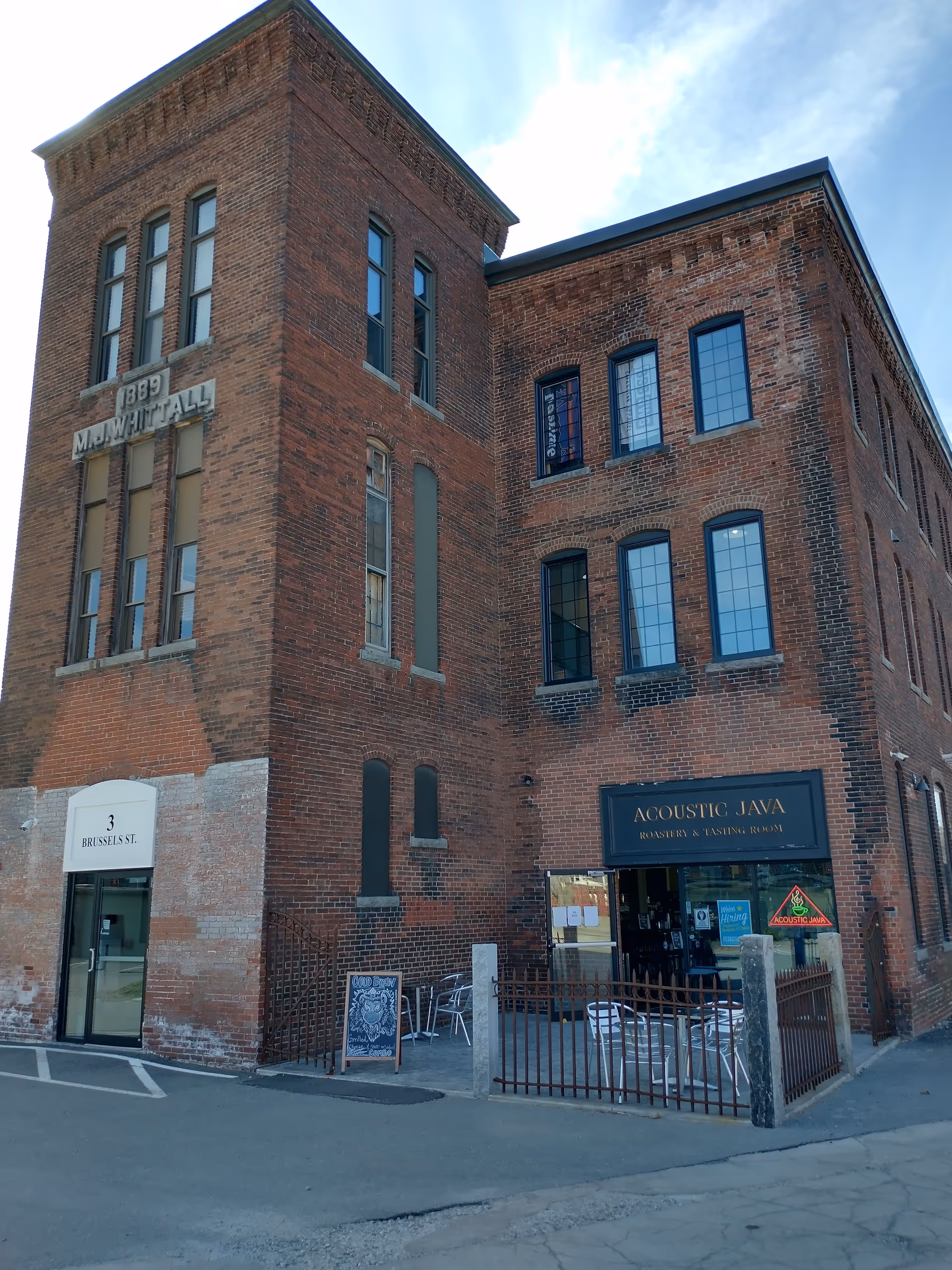 Brick, three-story building with large windows and outdoor seating, home to Acoustic Java cafe.