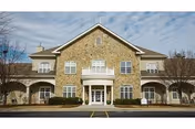 Two-story stone Wesley Commons senior living facility with central entrance and manicured landscaping.