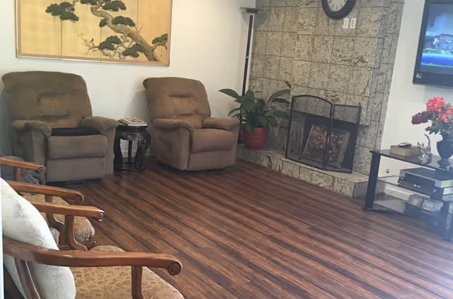 Cozy common living room with recliner chairs, fireplace, TV, and potted plants.