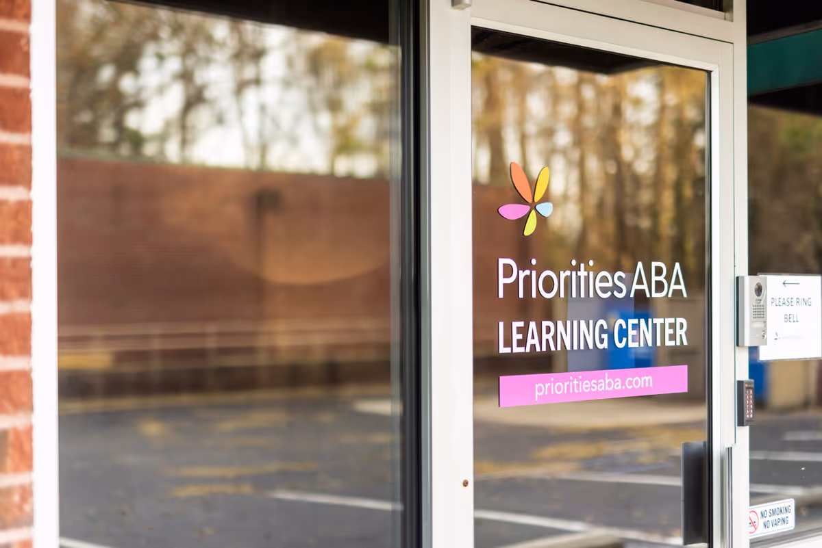 Glass entrance door shows Priorities ABA Learning Center branding and website.