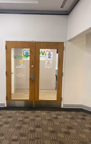 Wooden double doors with glass panels in a hallway, signs posted on them.